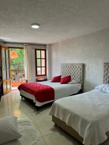 a bedroom with two beds and a window at Hotel La Candelaria in Ráquira