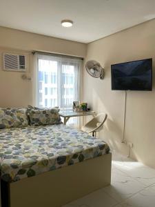 een slaapkamer met een bed, een bank en een tafel bij Cozy Studio with Netflix and Pool near Cubao and Greenhills in Manilla