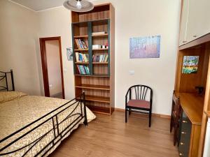 a bedroom with a bed and a chair and a book shelf at La Panchina sul Corso in Grassano