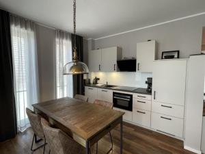 - une cuisine avec une table en bois et des placards blancs dans l'établissement 4Hafenzeiten - Ferienwohnung NIE 8 Albatros, à Niendorf