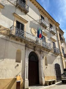a building with a door with two flags on it at La Panchina sul Corso in Grassano