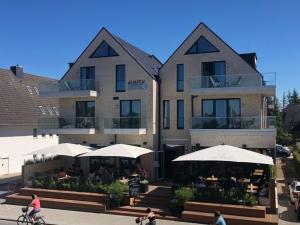 un bâtiment avec des tables et des parasols devant lui dans l'établissement 4Hafenzeiten - Ferienwohnung NIE 10 Gertrud II, à Niendorf