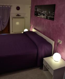 a bedroom with a purple bed and a nightstand with two lamps at B&B da Rosario in Campomaggiore