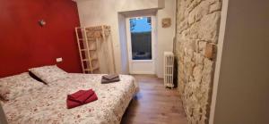 1 dormitorio con cama y pared de piedra en Gîte du Rocher des Commères, en Sirod
