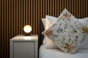 ein Kissen auf einem Bett neben einem Nachttisch mit einer Lampe in der Unterkunft Guest House A Loja do Cantoneiro in Albergaria-a-Velha