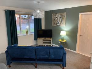 a living room with a blue couch and a television at The Uxbridge Suite in Hednesford