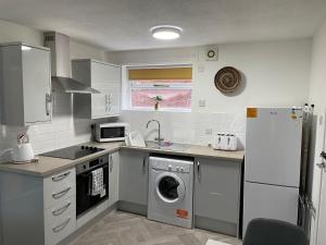 uma cozinha com uma máquina de lavar roupa e um frigorífico em The Uxbridge Suite em Hednesford
