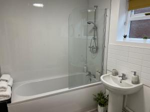 uma casa de banho com um chuveiro, um lavatório e uma banheira em The Uxbridge Suite em Hednesford