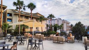 d'une terrasse avec des tables, des chaises et des palmiers. dans l'établissement Side Zeugma Hotel - Adult Only 16 Plus, à Sidé