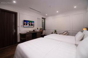 a bedroom with two beds and a desk and a tv at Hillary Hanoi Hotel in Hanoi