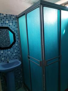 a blue shower stall with a sink and a mirror at Divino Niño Hotel in Leticia