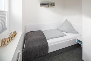 ein weißes Bett mit einem grauen Kissen darauf in der Unterkunft Haus Bielefeld Ferienwohnung 12 in Norderney