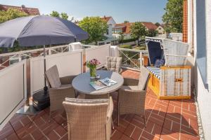 eine Terrasse mit einem Tisch, Stühlen und einem Sonnenschirm in der Unterkunft Haus Bielefeld Ferienwohnung 12 in Norderney