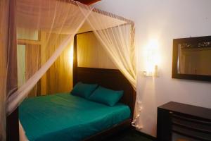 a bedroom with a green bed with a canopy at Villa Nadya Guesthouse in Pilana