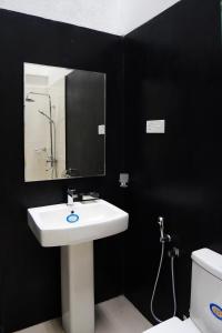 a bathroom with a sink and a mirror and a toilet at Villa Nadya Guesthouse in Pilana