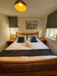 a bedroom with a large bed with two pillows at Peak View - Modern Cottage in Buxton