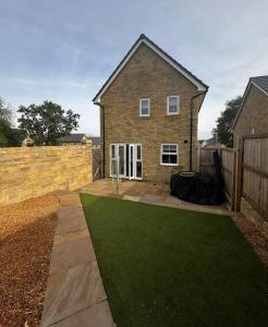 a brick house with a green lawn in front of it at Peak View - Modern Cottage in Buxton
