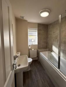 a bathroom with a tub and a toilet and a sink at Peak View - Modern Cottage in Buxton