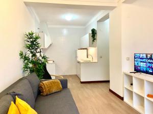 a living room with a gray couch and a tv at Ericeira Panoramic Sea View Apartments in Ericeira