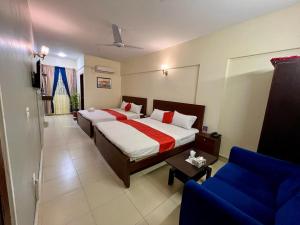 a bedroom with a bed and a blue couch at Hotel 7 DHA in Karachi
