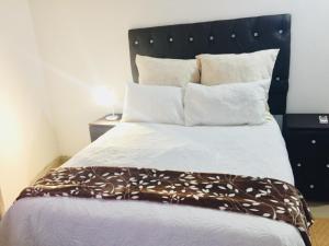 a bed with a black headboard and white sheets and pillows at Emakhabeleni Bed & Breakfast in Manguzi
