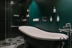 a bathroom with a tub and a green wall at Art Legacy Hotel Baixa-Chiado in Lisbon