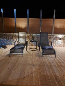 dwa krzesła i stół na drewnianej podłodze w obiekcie Villas Kertezi w Kalawricie