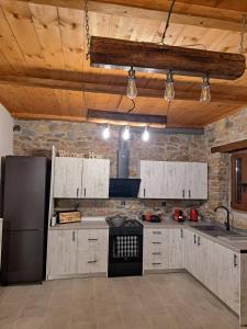 a kitchen with white cabinets and a black refrigerator at Villas Kertezi in Kalavrita