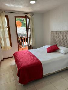 a bedroom with a large bed with a red blanket at Hotel La Candelaria in Ráquira