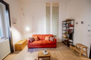 a living room with an orange couch and a book shelf at Vintage and Design in the Heart of Vibrant Pigneto in Rome