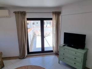 uma sala de estar com televisão e janela em New Cozy Apartment em Vilamoura