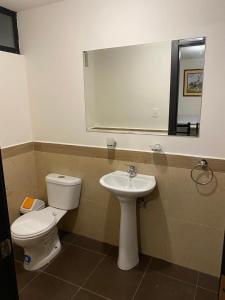 a bathroom with a toilet and a sink and a mirror at Hermosa Suite para largas estadías con parqueadero in Quito