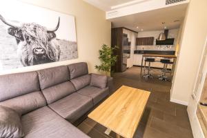 una sala de estar con sofá y una foto de una vaca en Piso céntrico y acogedor. Opción parking gratuito. en Jaén