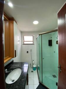 a bathroom with a sink and a glass shower at Loft Frente ao Mar com Piscina Aquecida, Sauna Privada - Arraial do Cabo in Arraial do Cabo
