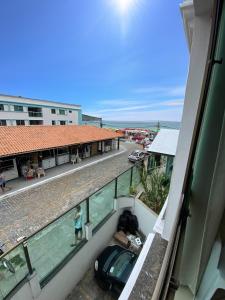 a person standing on a balcony of a building with a car at Loft Frente ao Mar com Piscina Aquecida, Sauna Privada - Arraial do Cabo in Arraial do Cabo