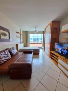 a living room with a couch and a flat screen tv at Loft Frente ao Mar com Piscina Aquecida, Sauna Privada - Arraial do Cabo in Arraial do Cabo