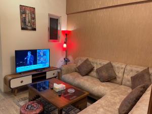 uma sala de estar com um sofá e uma televisão de ecrã plano em Al-Rabie Hotel & Apartments em Bagdá