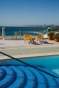 a swimming pool with chairs and a view of the water at Sobre el mar con vistas a las Dunas de Maspalomas in San Agustin