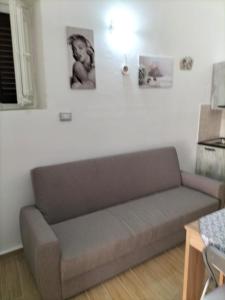 un sofá en una sala de estar con dos cuadros en la pared en Holiday House LORE&ALEX en Balestrate