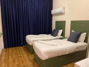 two beds in a room with blue curtains at Al-Rabie Hotel & Apartments in Baghdād