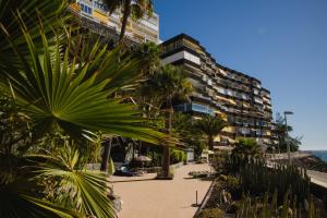 a beach with palm trees and a large building at Sobre el mar con vistas a las Dunas de Maspalomas in San Agustin