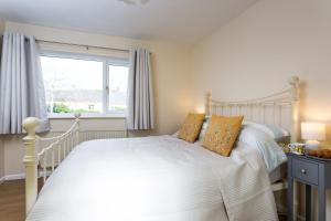 a bedroom with a white bed and a window at April Cottage in Stow on the Wold