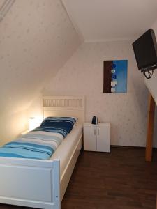 a bedroom with a bed and a flat screen tv at Gästehaus Atrico Schleuse Wg 1 in Surwold
