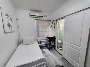 a bedroom with a bed and a desk and a door at Groenewald's Haven in Nelspruit