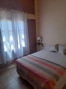 ein Schlafzimmer mit einem Bett mit gestreifter Decke und einem Fenster in der Unterkunft cabañas oliv- san rafael-mendoza in San Rafael