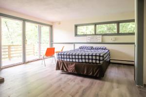 a bedroom with a bed and a chair and windows at Stark Mountain Sanctuary in Waitsfield