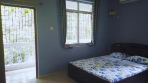 een slaapkamer met een bed en 2 ramen bij Yago's Hideout in Bogmalo