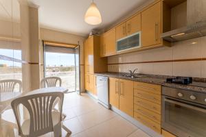 a kitchen with wooden cabinets and a table and chairs at T2 Arte Xávega in Nazaré