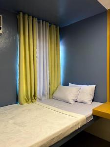 a bed in a room with yellow curtains at Mar Azul Travellers Inn and SPA in San Remigio