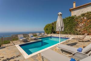 ストウパにあるSOFIA, Luxury Stone Villa in Stoupa with Private Pool, BBQ and Amazing Sea Viewのスイミングプール(椅子、パラソル付)が備わるヴィラです。